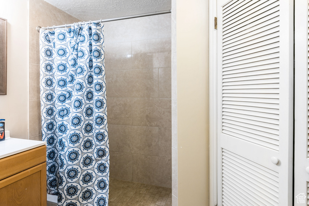 Bathroom with curtained shower, a textured ceiling, and vanity