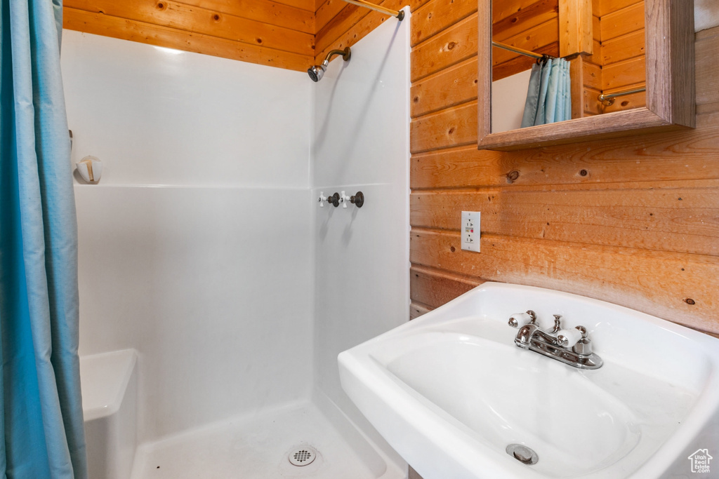 Bathroom featuring a shower with curtain, sink, and wooden walls