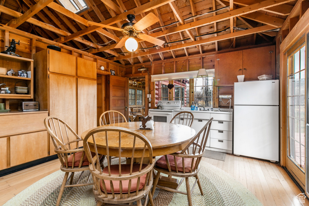 Dining area with wood walls, plenty of natural light, and light hardwood / wood-style floors