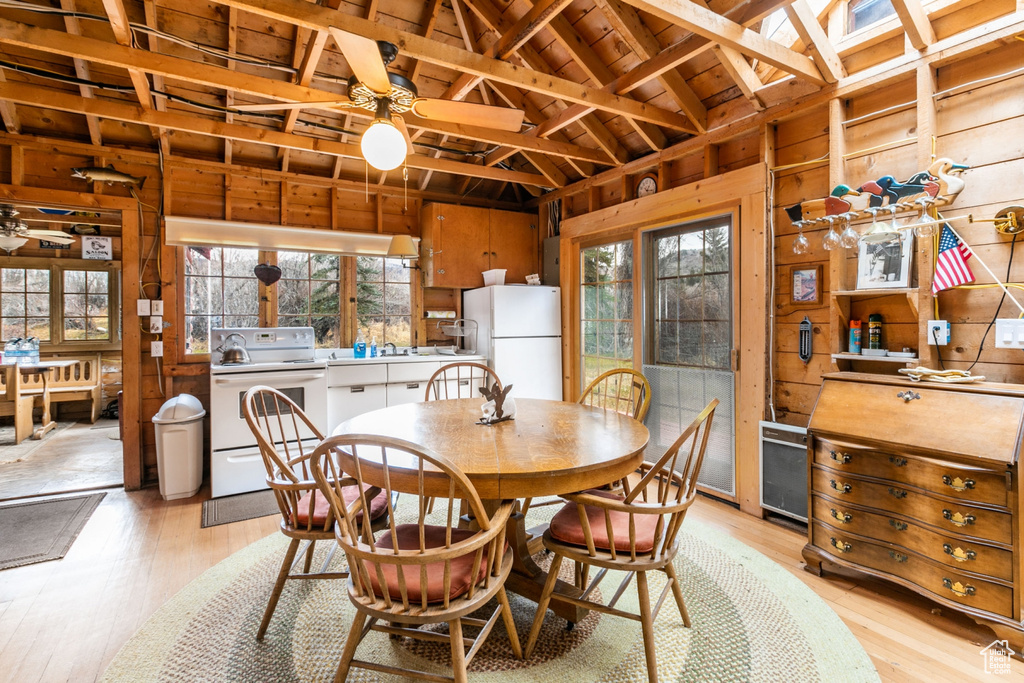Dining area with wooden walls, light hardwood / wood-style floors, and ceiling fan