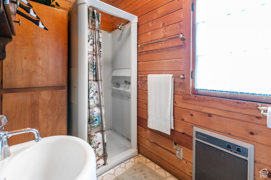 Bathroom featuring sink, wooden walls, a shower, and tile flooring