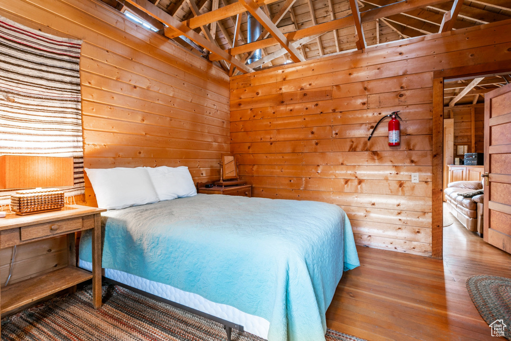 Bedroom with wood walls and hardwood / wood-style floors