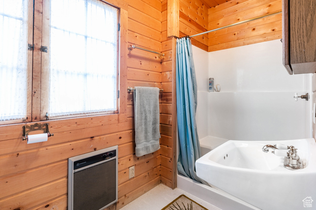Bathroom with wooden walls, a wealth of natural light, and sink
