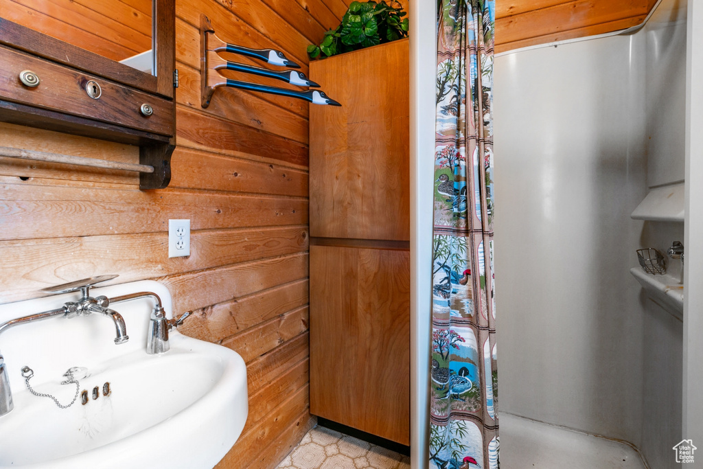 Bathroom with wood walls, sink, tile flooring, and wooden ceiling