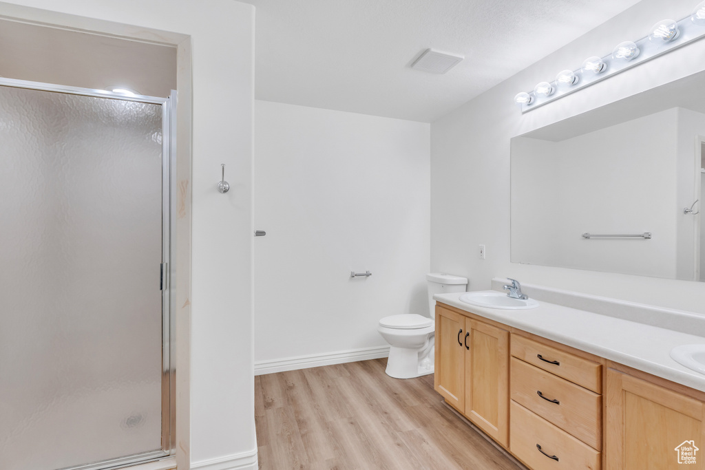 Bathroom featuring wood-type flooring, toilet, walk in shower, and dual vanity
