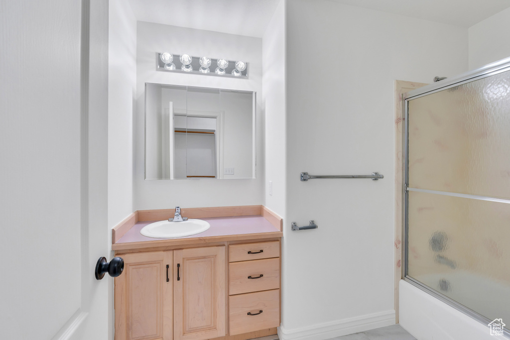 Bathroom with combined bath / shower with glass door and vanity