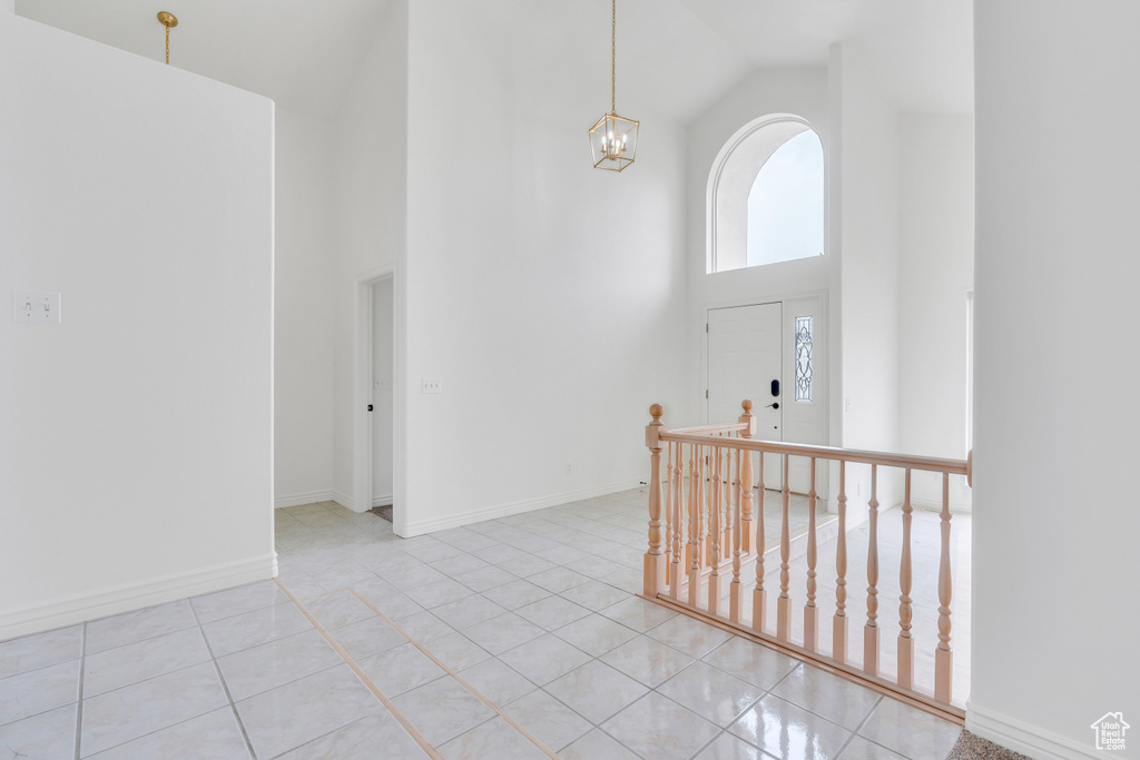 Foyer entrance with an inviting chandelier, light tile flooring, and high vaulted ceiling