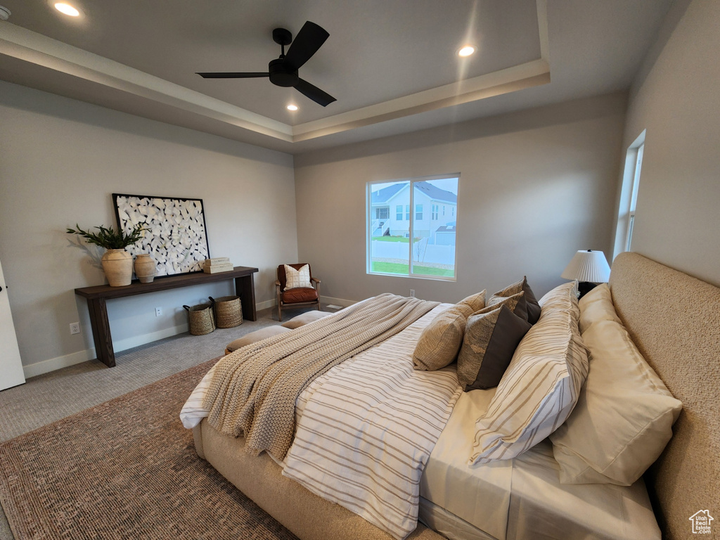Bedroom featuring light colored carpet, ceiling fan, and a tray ceiling