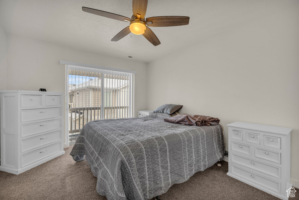 Bedroom with dark colored carpet, access to exterior, and ceiling fan