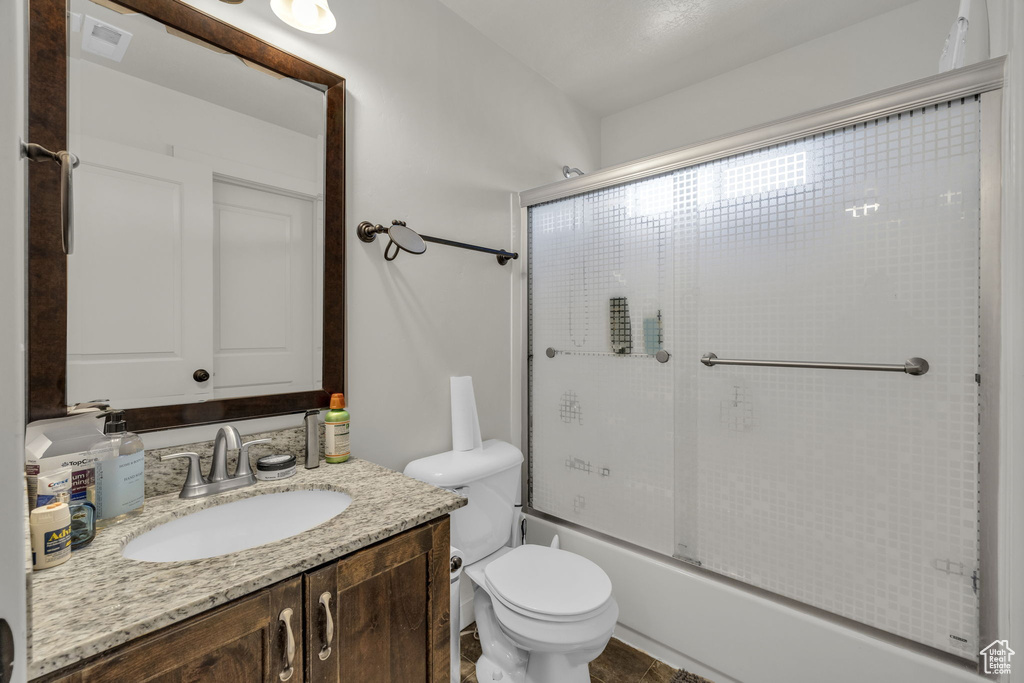 Full bathroom featuring vanity, toilet, tile flooring, and enclosed tub / shower combo