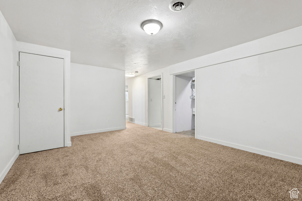 Basement featuring a textured ceiling and light colored carpet