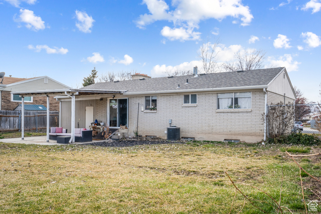 Back of property with a lawn, central AC unit, a patio area, and an outdoor living space