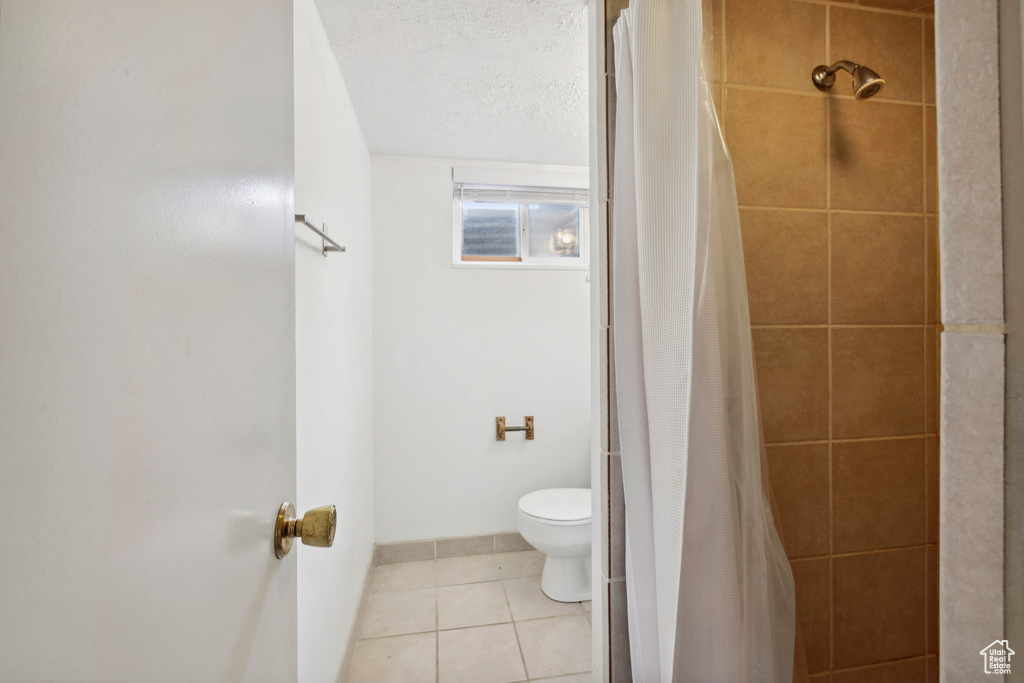 Bathroom with toilet, tile flooring, and a textured ceiling