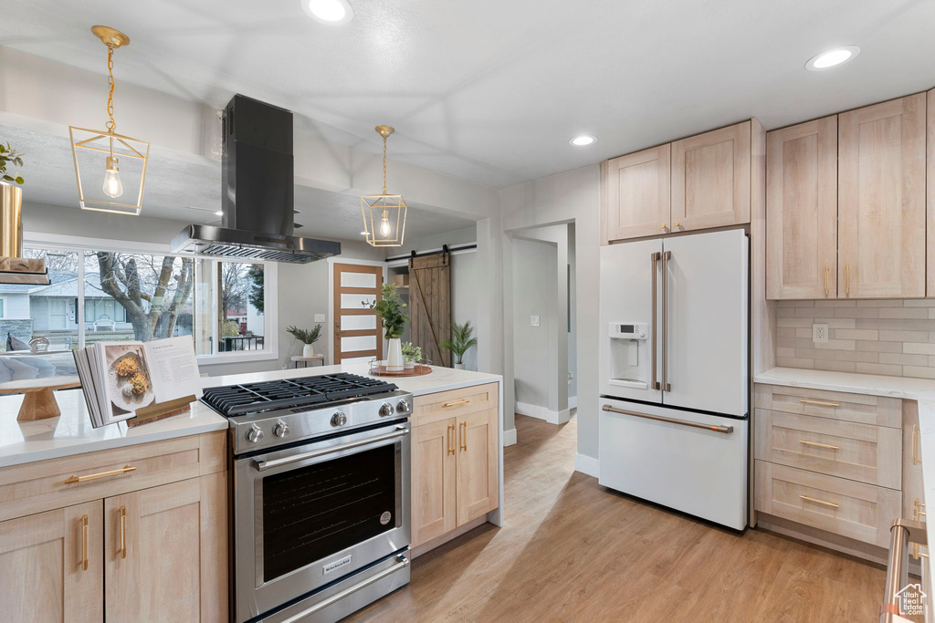 Kitchen featuring high end white fridge, island range hood, a barn door, gas stove, and pendant lighting