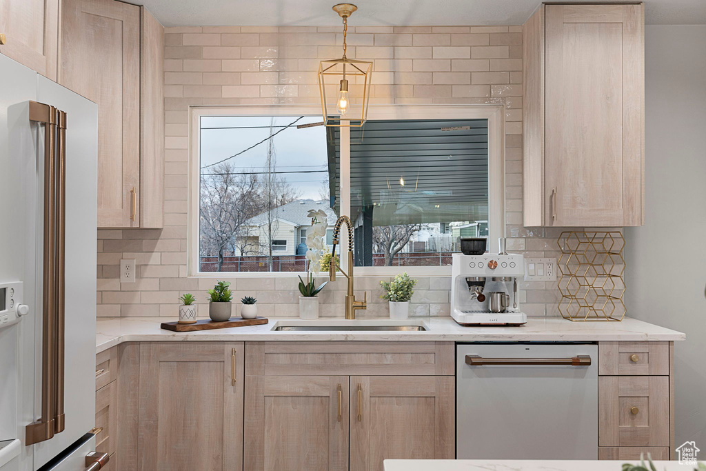 Kitchen featuring dishwashing machine, sink, high end refrigerator, light brown cabinetry, and backsplash