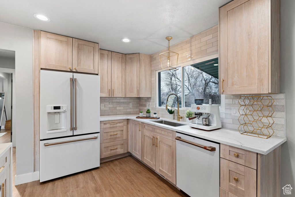 Kitchen with white appliances, tasteful backsplash, light hardwood / wood-style floors, and sink