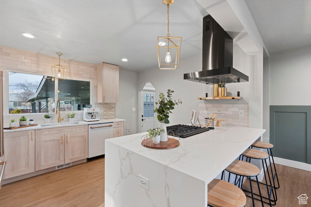 Kitchen featuring tasteful backsplash, sink, light hardwood / wood-style floors, white dishwasher, and island range hood