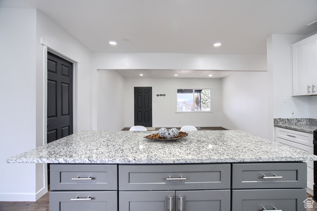 Kitchen featuring a kitchen island, gray cabinets, light stone countertops, and dark hardwood / wood-style floors