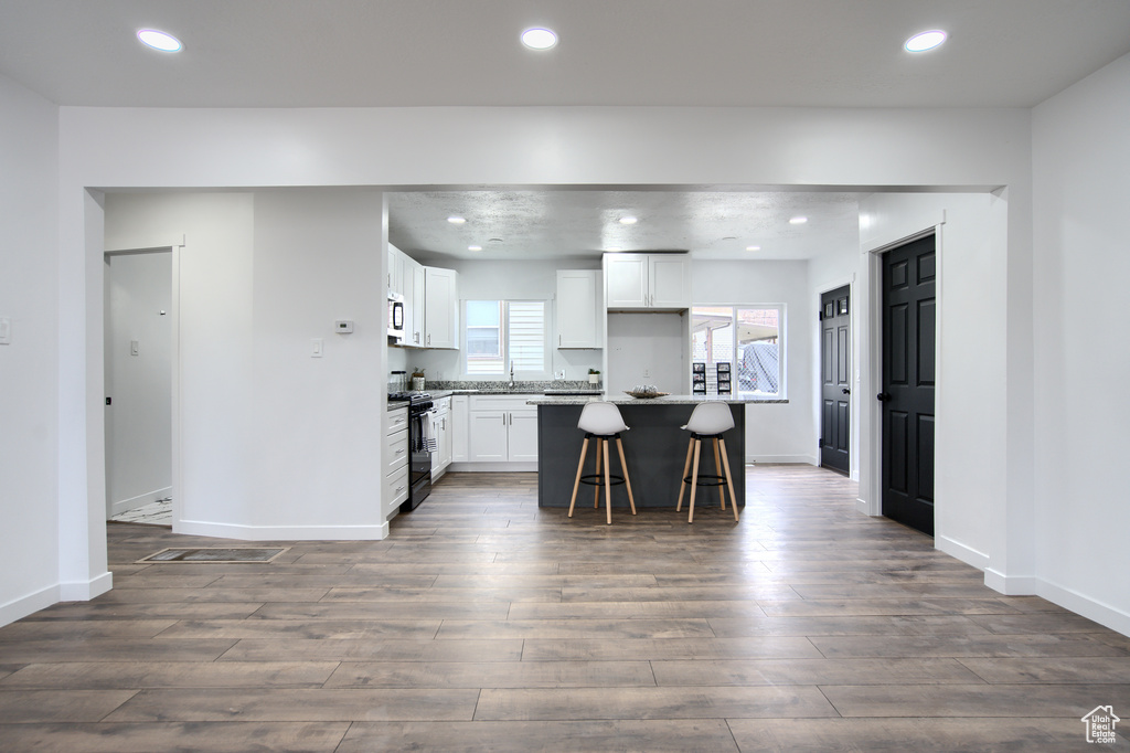 Kitchen with white cabinets, dark hardwood / wood-style flooring, and a breakfast bar