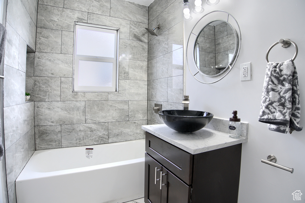Bathroom featuring tiled shower / bath combo and vanity