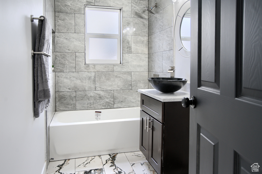 Bathroom featuring oversized vanity, tile flooring, and tiled shower / bath