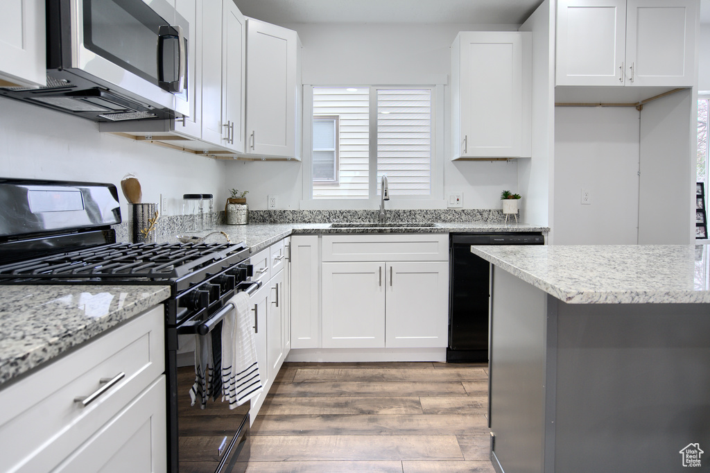 Kitchen featuring black appliances, dark hardwood / wood-style floors, sink, and white cabinetry