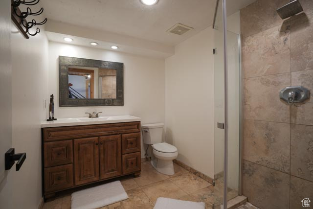 Bathroom with tiled shower, oversized vanity, tile flooring, and toilet