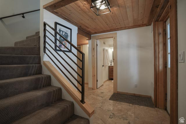 Staircase featuring wooden ceiling and light tile floors