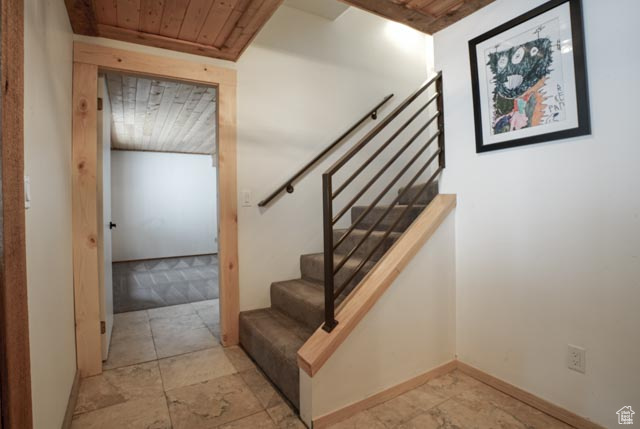 Stairway featuring light tile floors and wood ceiling