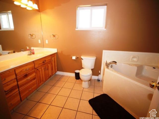 Bathroom featuring vanity, toilet, a bathing tub, and tile floors