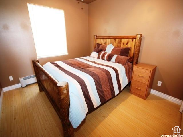 Bedroom featuring a baseboard heating unit and light hardwood / wood-style floors