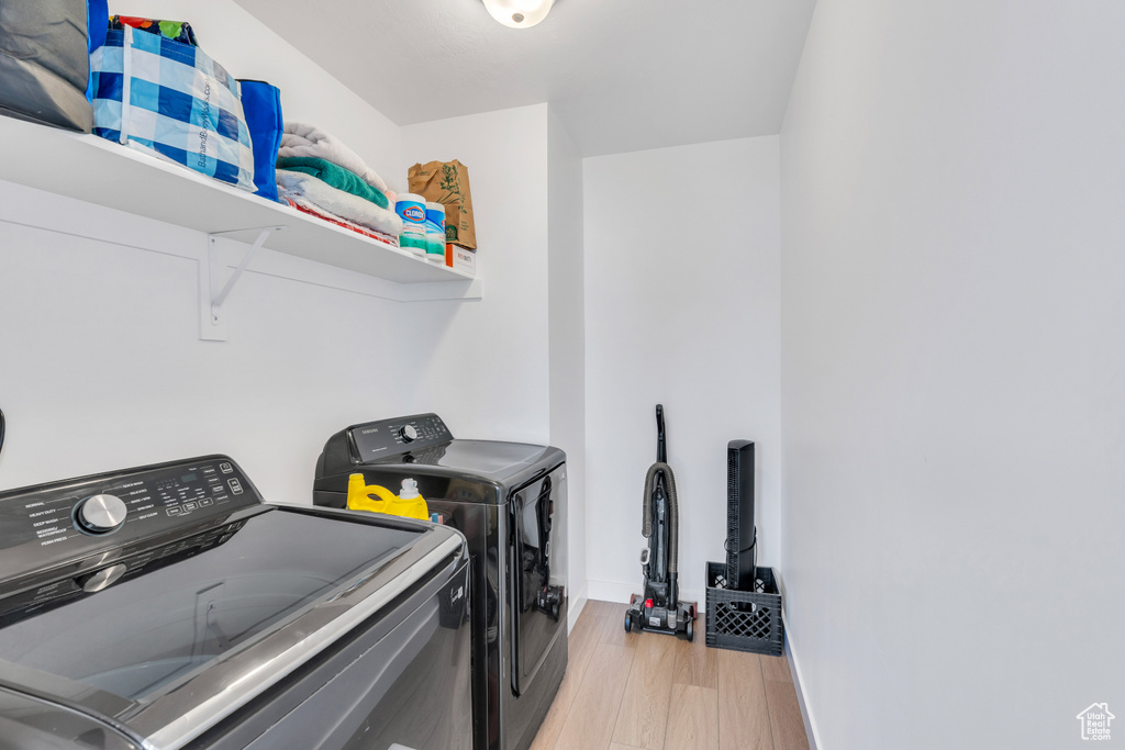 Laundry area featuring light hardwood / wood-style flooring and washing machine and clothes dryer