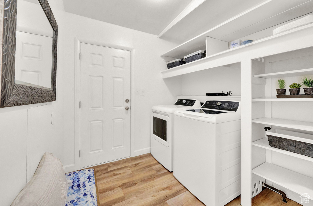 Clothes washing area featuring washer and dryer and light hardwood / wood-style floors