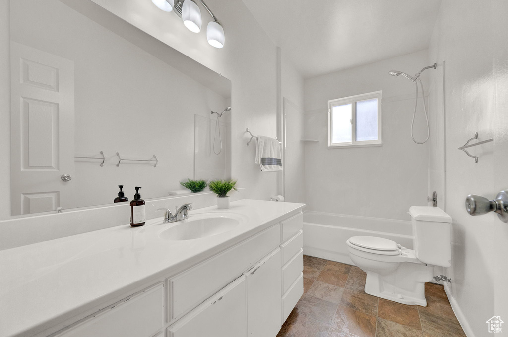Full bathroom with toilet, vanity with extensive cabinet space, tile floors, and tub / shower combination