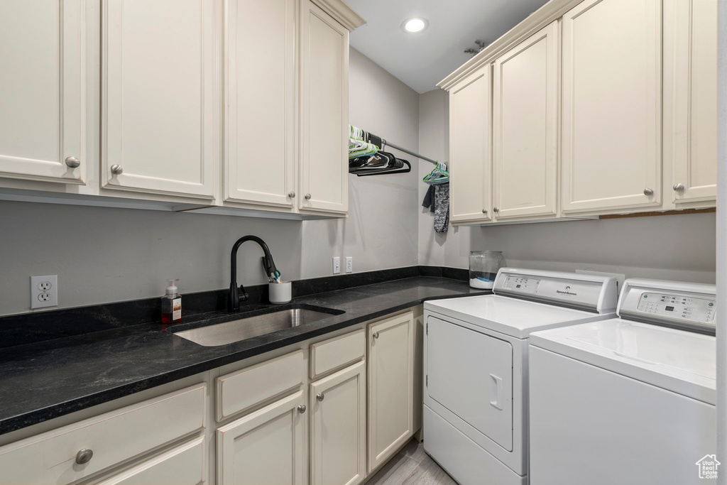 Laundry room featuring cabinets, sink, and washing machine and clothes dryer