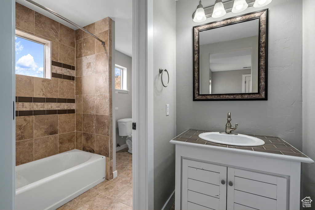Full bathroom featuring vanity, toilet, tiled shower / bath, and tile floors