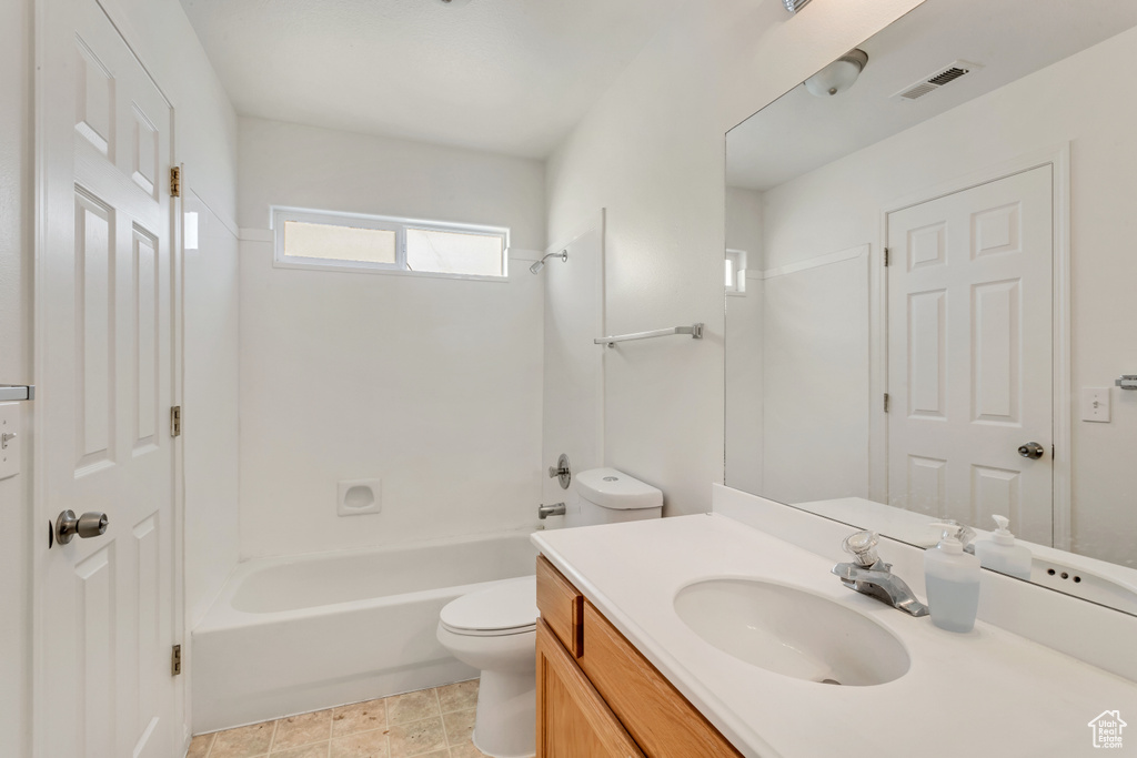 Full bathroom with tub / shower combination, vanity with extensive cabinet space, tile floors, and toilet