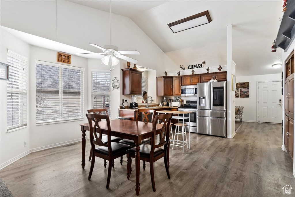 Dining space with high vaulted ceiling, hardwood / wood-style flooring, sink, and ceiling fan