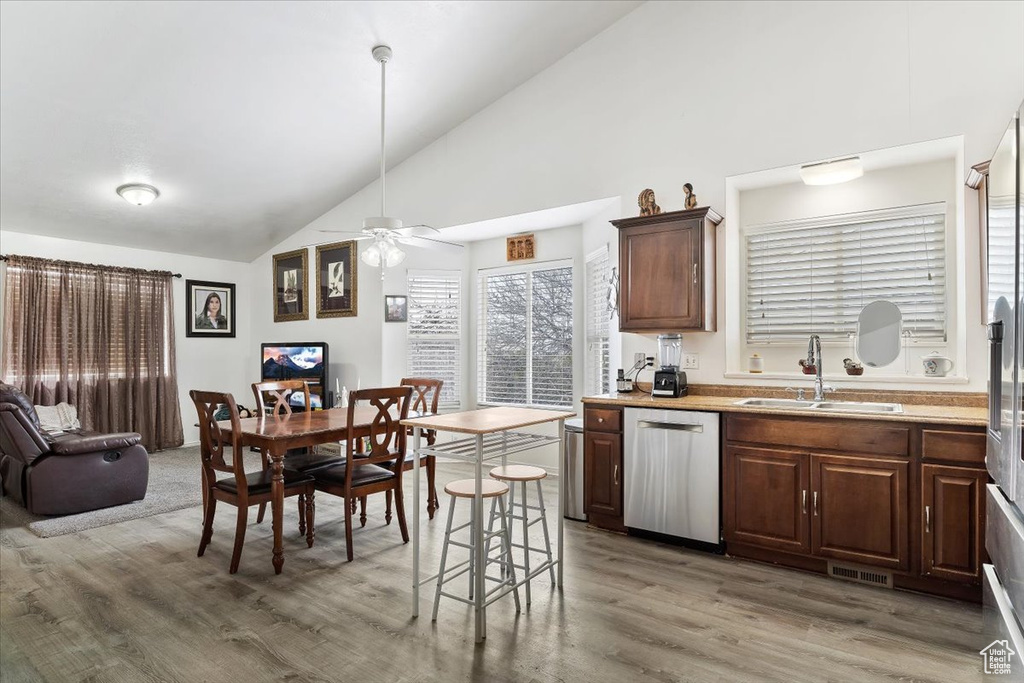 Kitchen featuring ceiling fan, dishwasher, light hardwood / wood-style floors, sink, and a breakfast bar