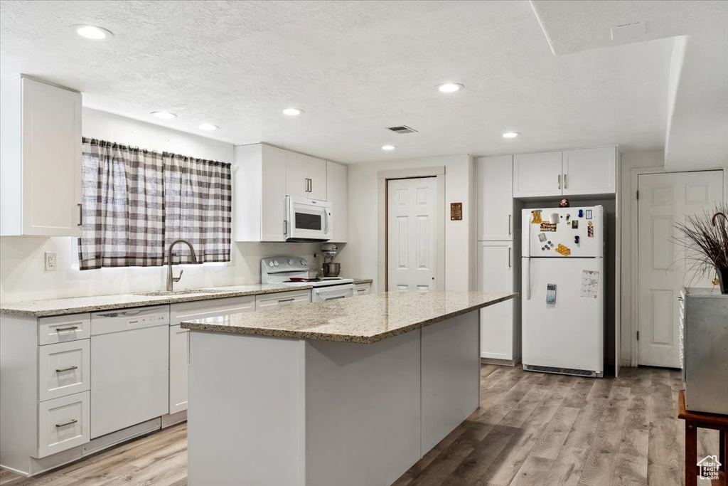 Kitchen featuring a kitchen island, light hardwood / wood-style flooring, white appliances, and white cabinets