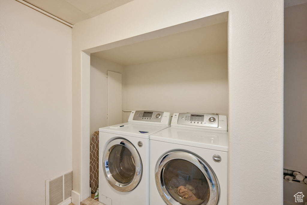 Clothes washing area with tile flooring and washer and clothes dryer