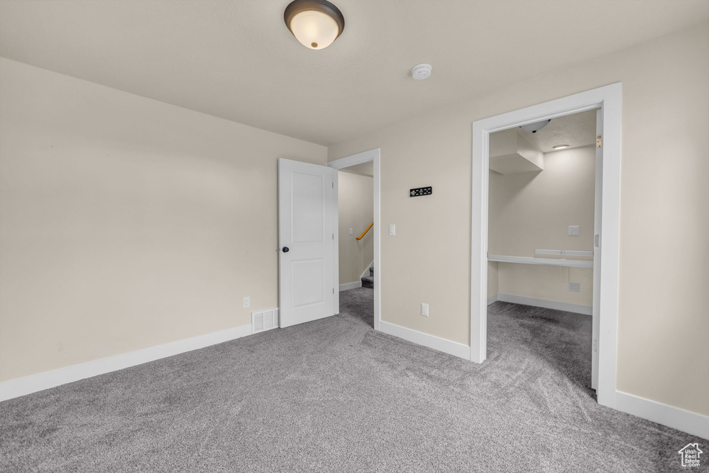 Unfurnished bedroom with a spacious closet, light colored carpet, and a closet