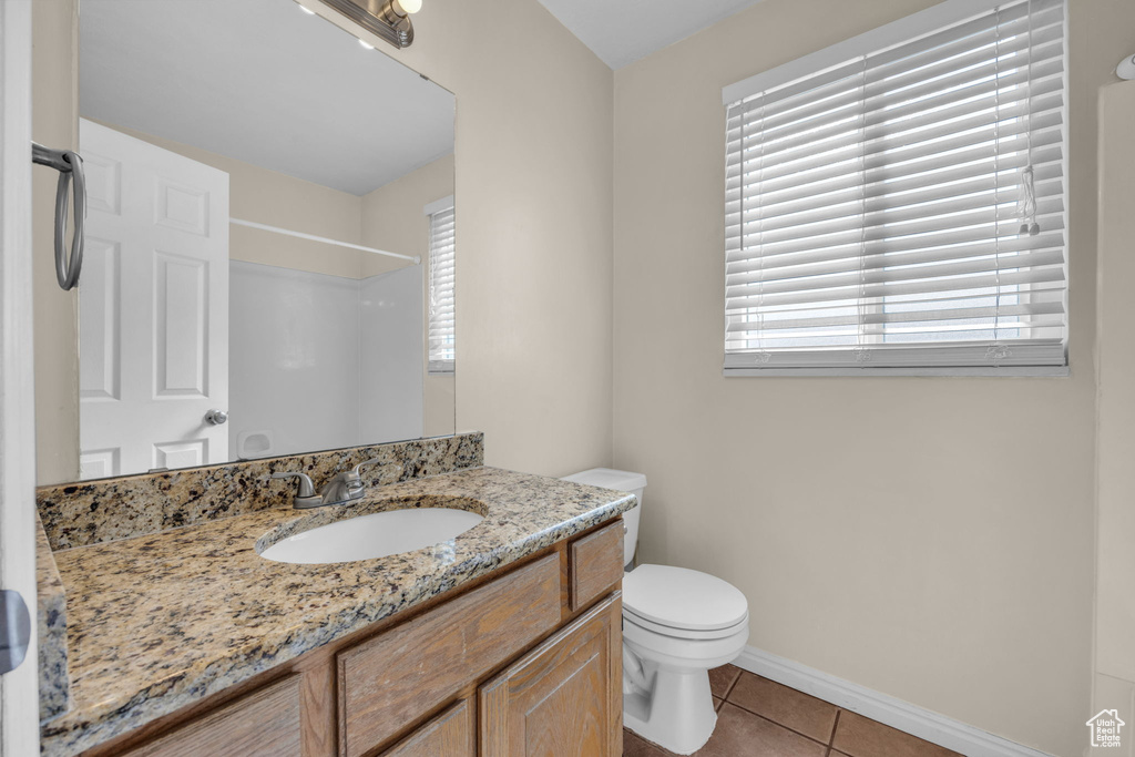 Bathroom with tile floors, a wealth of natural light, toilet, and large vanity