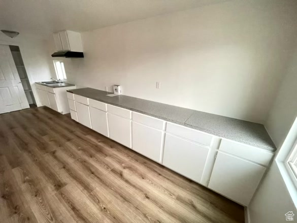 Kitchen with wood-type flooring and white cabinets