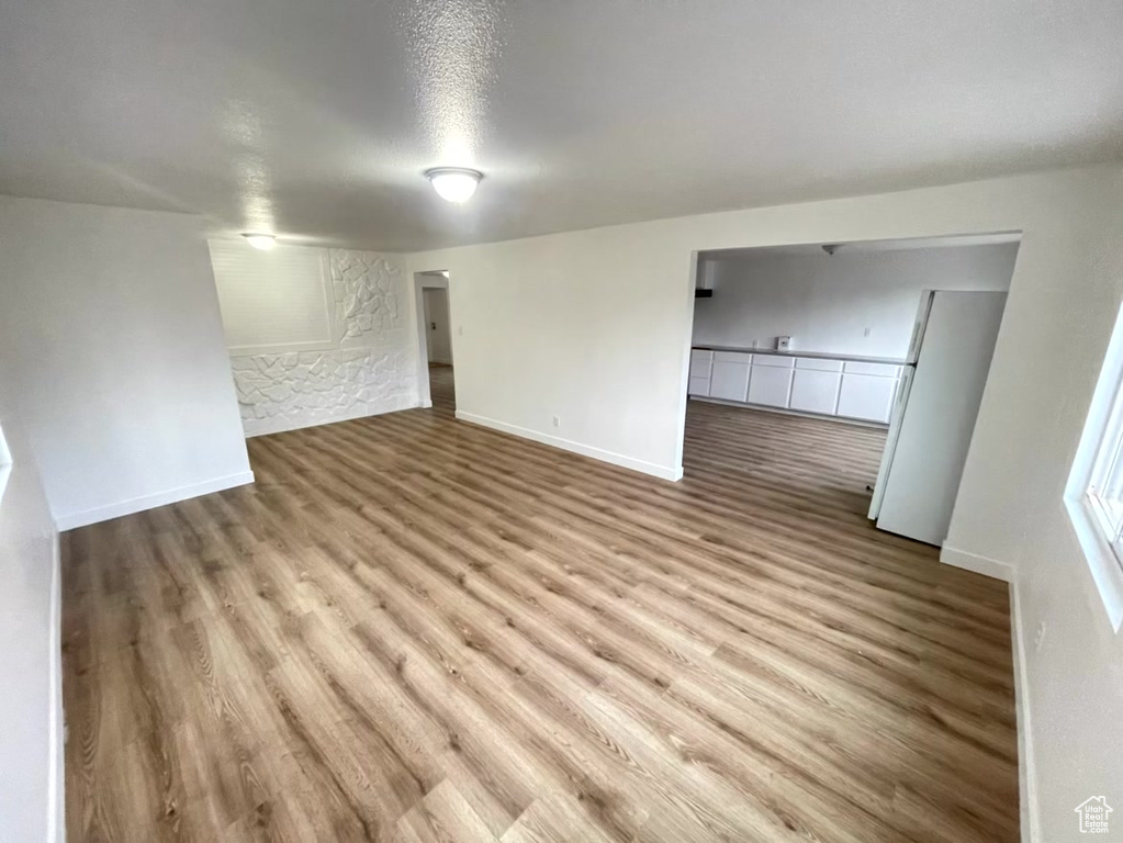 Empty room with light hardwood / wood-style flooring and a textured ceiling