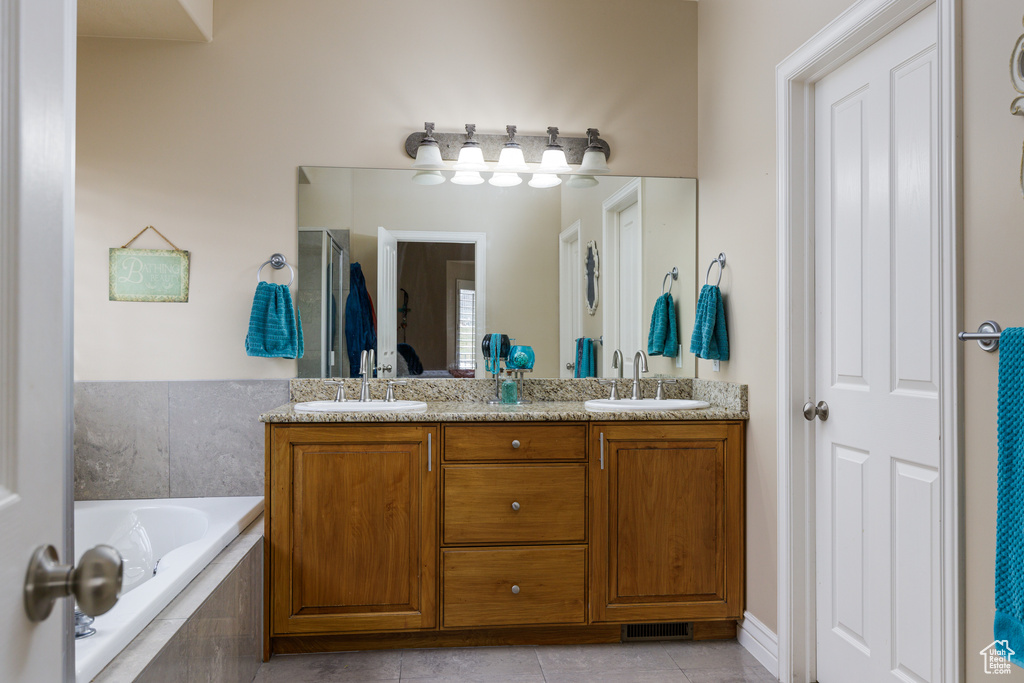 Bathroom with dual bowl vanity, tile flooring, and tiled tub