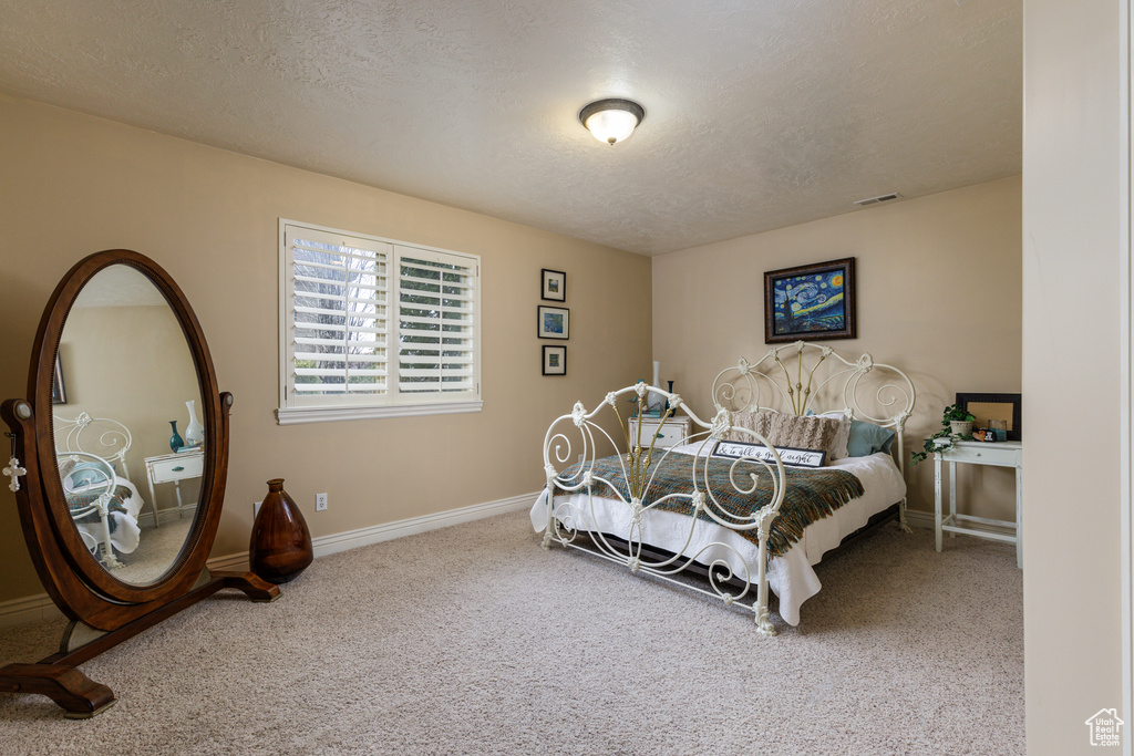 Bedroom featuring a textured ceiling and light colored carpet