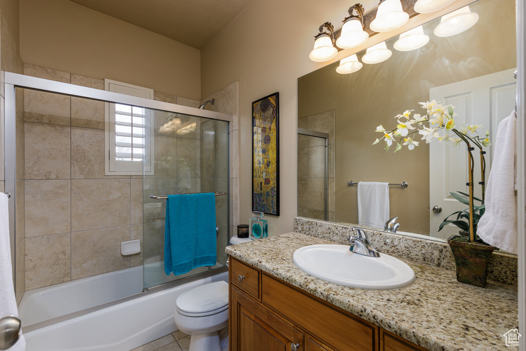 Full bathroom with large vanity, tile floors, toilet, and shower / bath combination with glass door