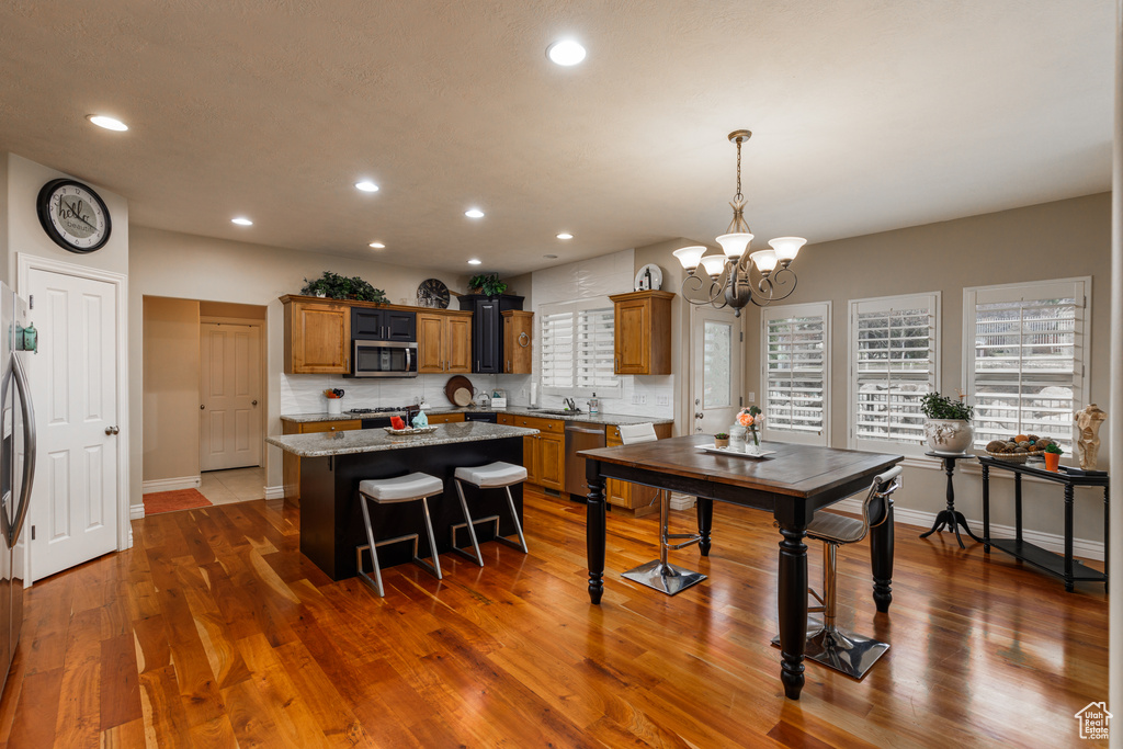 Kitchen featuring a chandelier, light stone counters, stainless steel appliances, and dark wood-type flooring