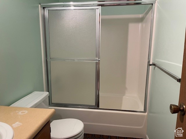 Full bathroom with combined bath / shower with glass door, vanity, toilet, and tile flooring